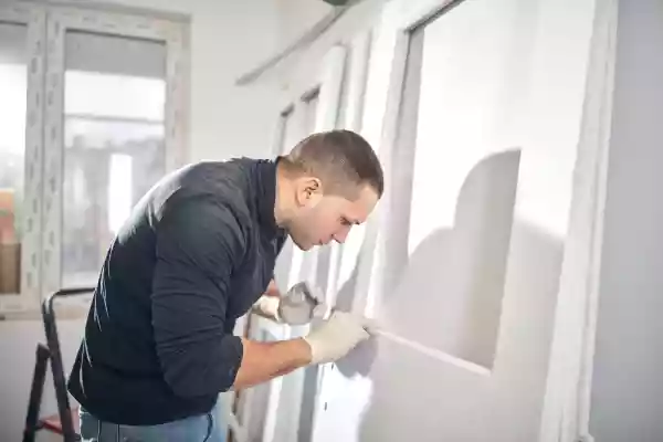 Un menuisier installant une porte vitrée intérieur avec soins.